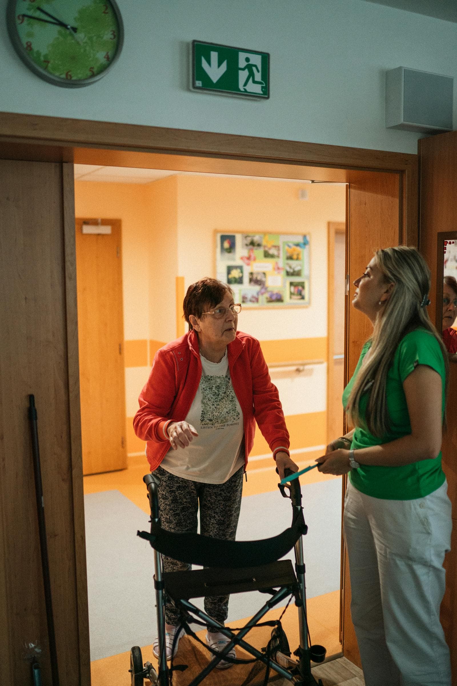 A caregiver assists a senior using a walker in a care setting — typical 24-hour home care moment.