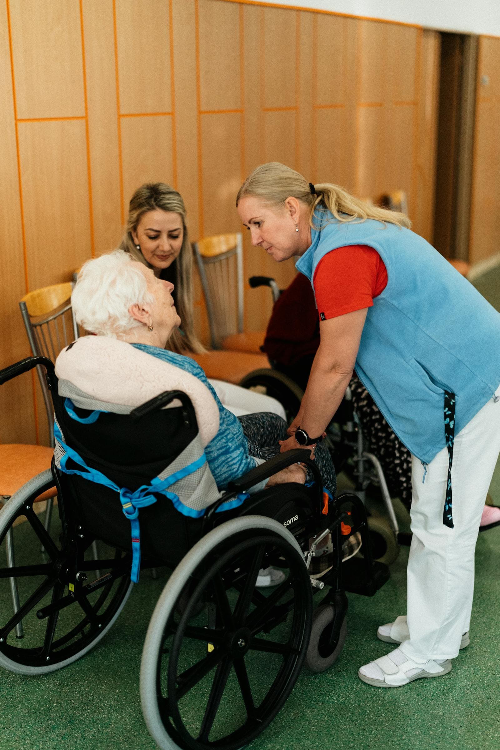 A caregiver speaks with an elderly woman in a wheelchair — the kind of attention 24-hour home care provides.